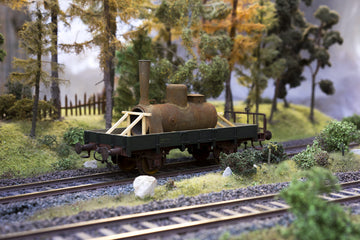 A detailed Hornby train engine on its tracks with lush green moss in the background. The combination of the miniature locomotive and natural elements adds depth and realism to the model railway scene.
