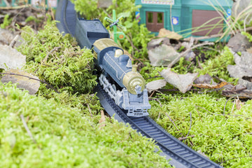 A detailed Hornby train set running along its tracks with lush green moss placed to the side. The natural moss adds a scenic, realistic touch to the miniature railway, enhancing the model landscape with an organic feel.